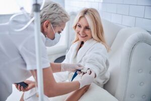 cheerful patient talking with doctor while receiving IV infusion