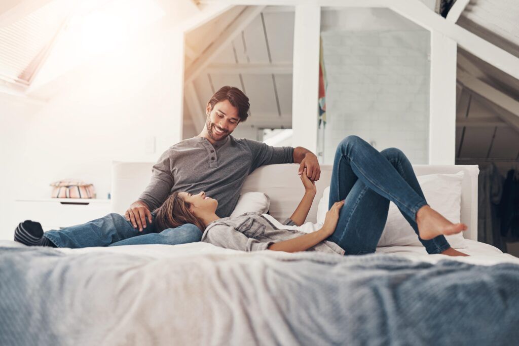 couple holding hands in bed in the morning