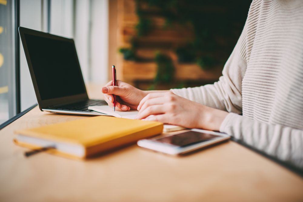 A person taking notes during an Online Therapy session