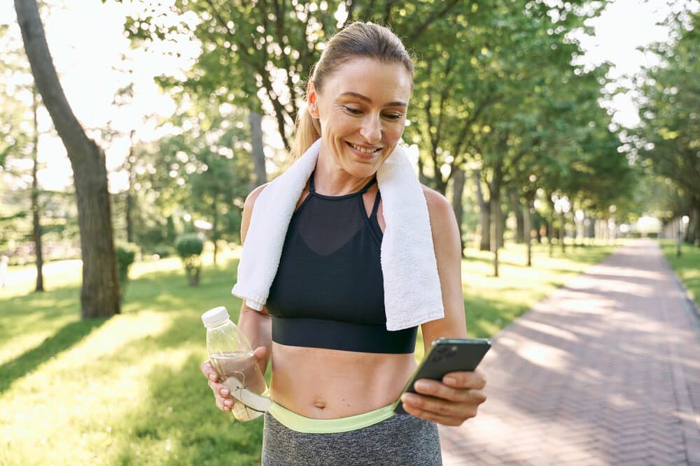 Cheerful fit woman in sportswear refreshing