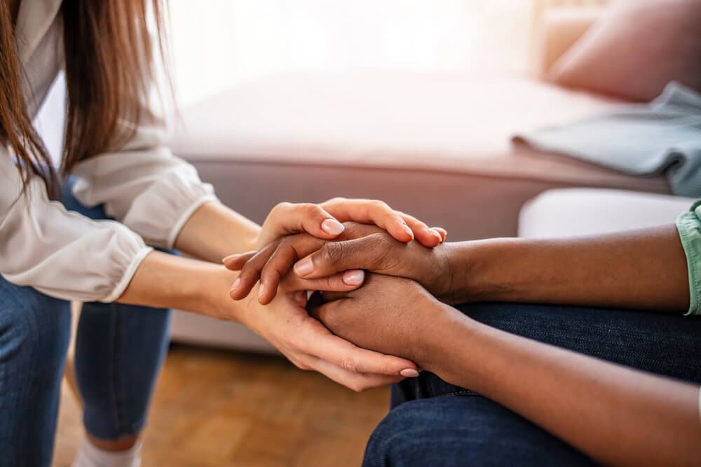 Friends hold hands during confidential talk