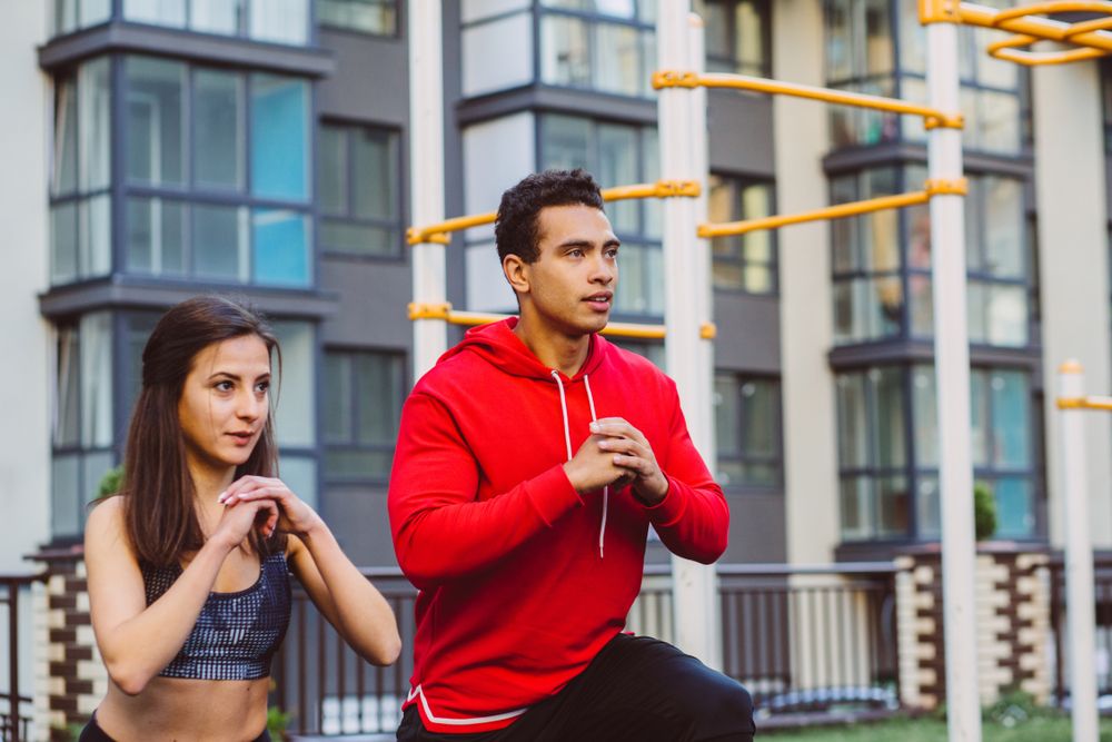 Young mixed race man and woman exercising on sports ground. man and woman doing exercise on street sports ground