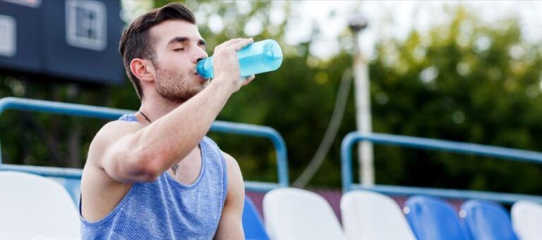 athletic man drinking water during workout