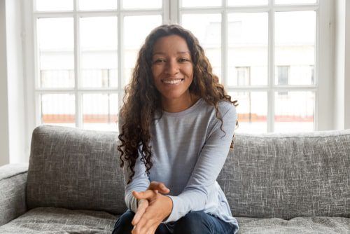 Smiling woman sitting on couch at home