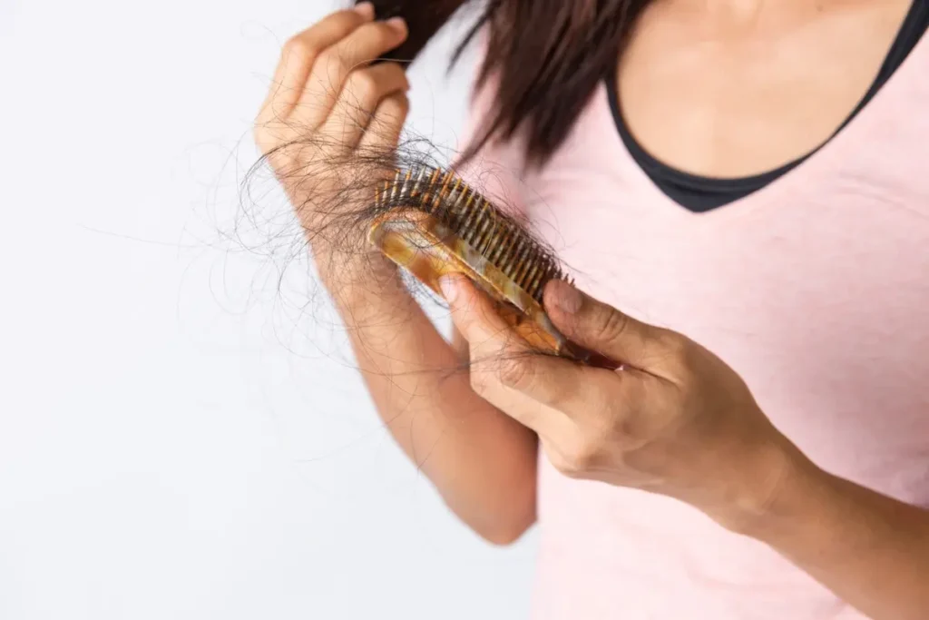 Hair loss treatment in Prescott: woman holds brush with shed hair after combing her hair