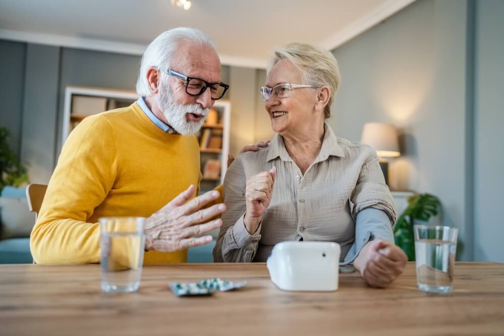 Senior woman measure blood pressure while her husband sit beside