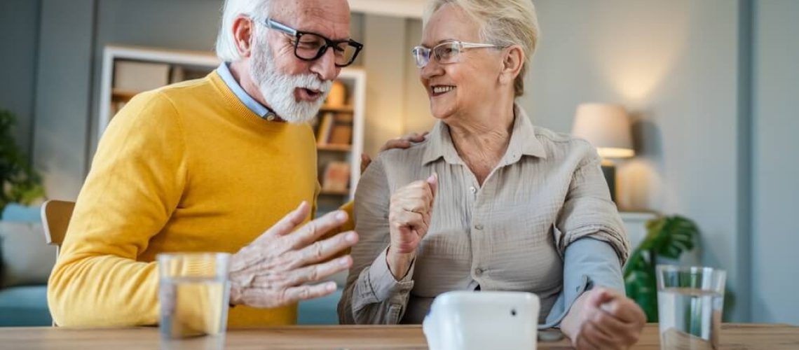 Senior woman measure blood pressure while her husband sit beside