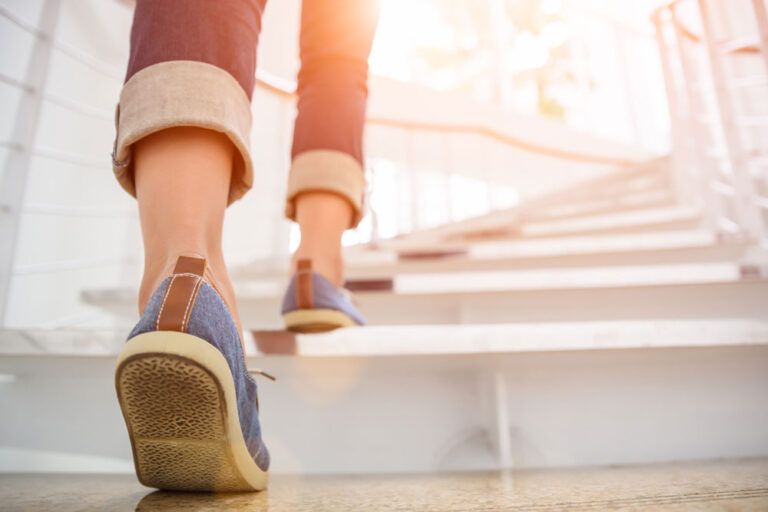 Young adult woman walking up the stairs with sun