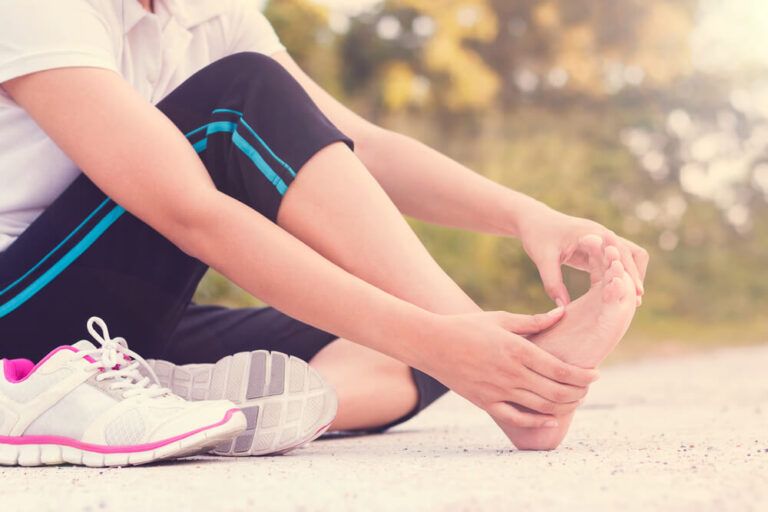 Young woman massaging her painful foot from exercising