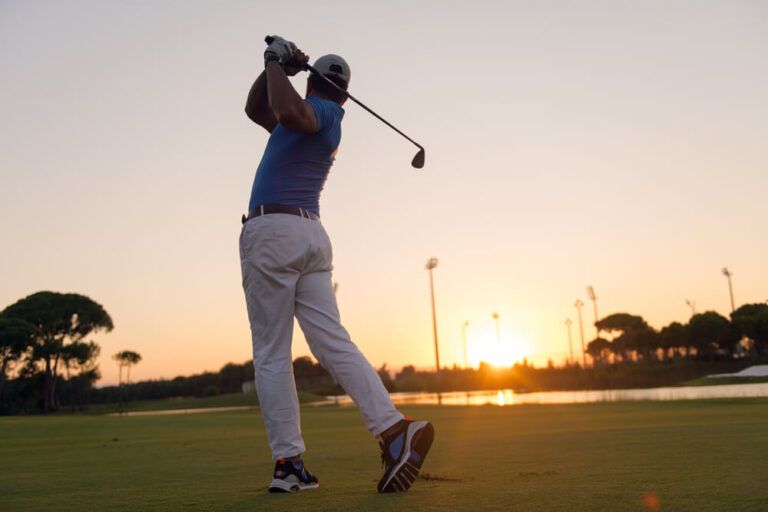 golfer hitting long shot with driver on course at beautiful sunset