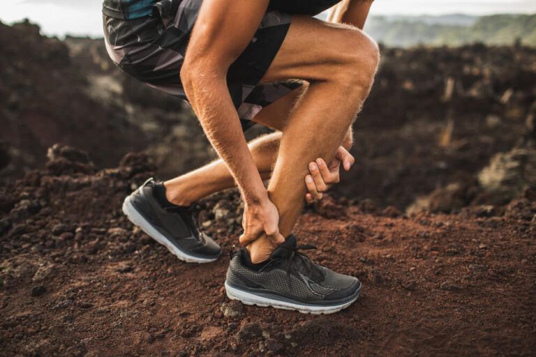 Man holding Achilles tendon by hands