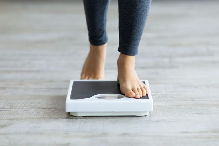 woman stepping on scales to measure her weight