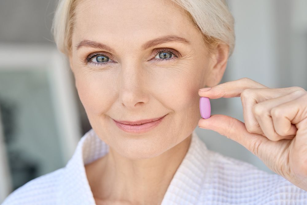 Closeup portrait of happy middle aged 50s woman holding pill taking dietary supplements