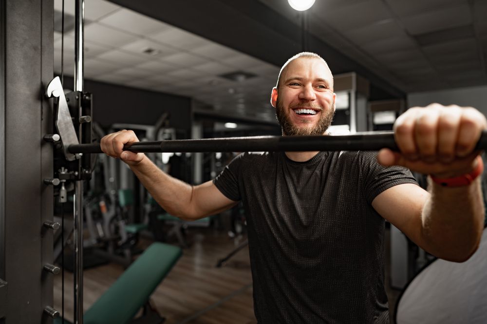 Cheerful smiling man bodybuilder standing in a gym