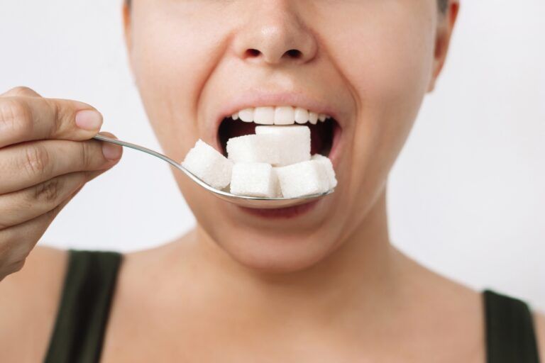 Cropped shot of a young woman holding a spoon with cubes of refined sugar near her mouth