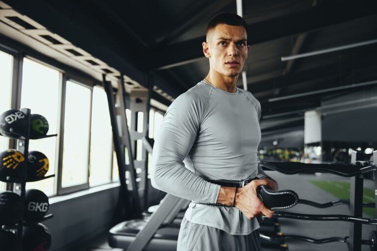 Dedicated athlete adjusts his leather gym belt, ensuring proper support and safety for a powerful workout routine
