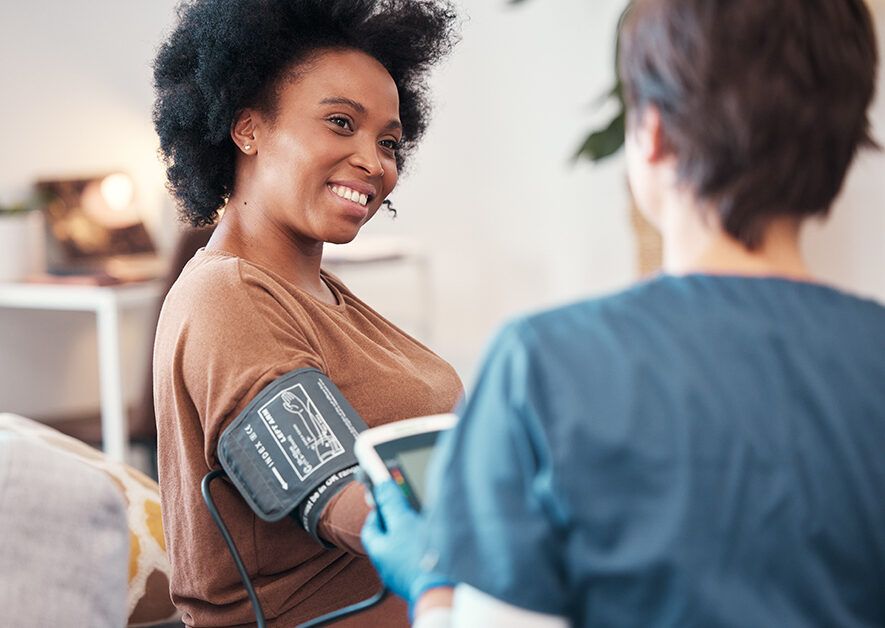 Patient and nurse in bedroom checking, blood pressure