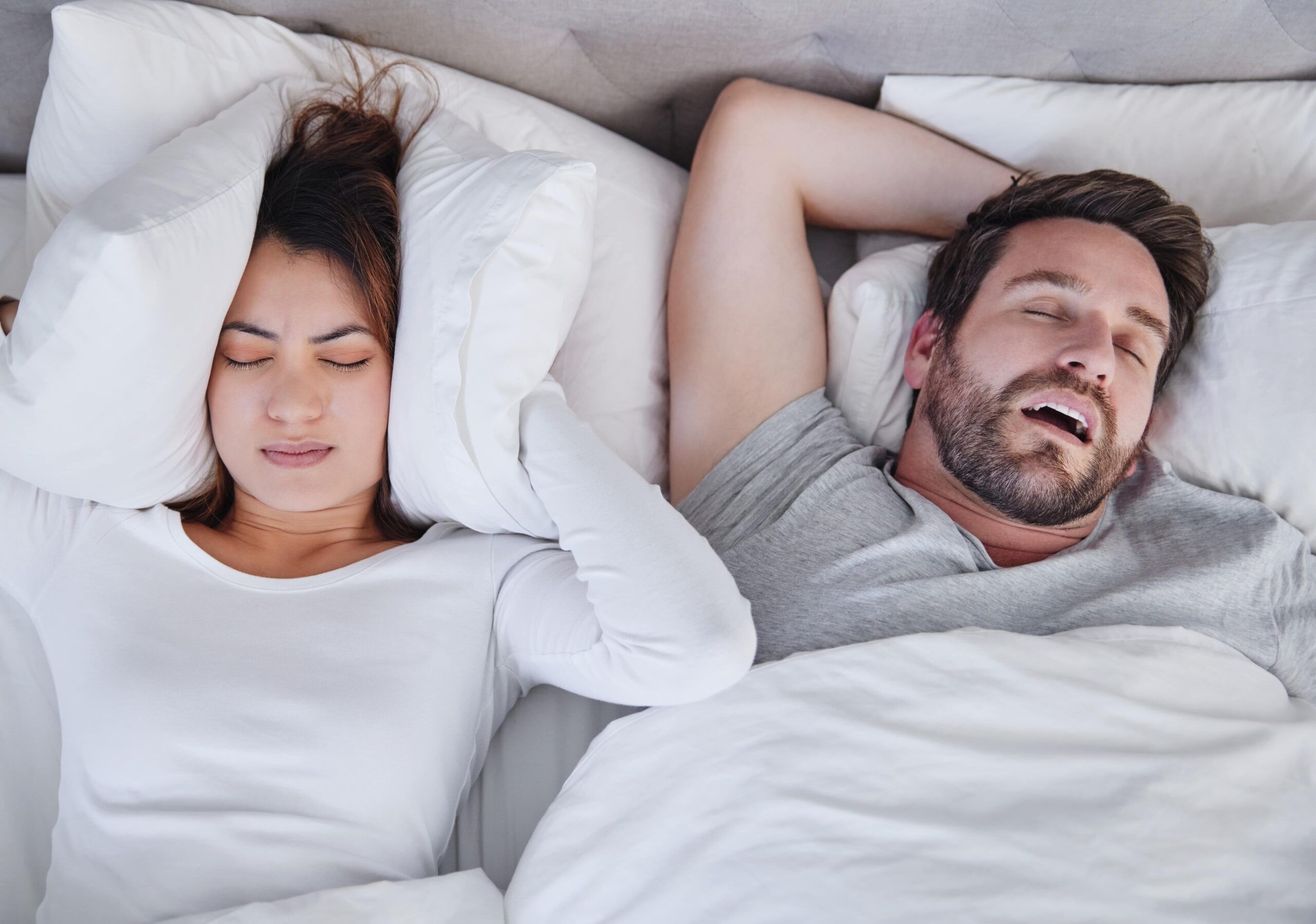 young woman struggling to sleep with her boyfriends snoring at home