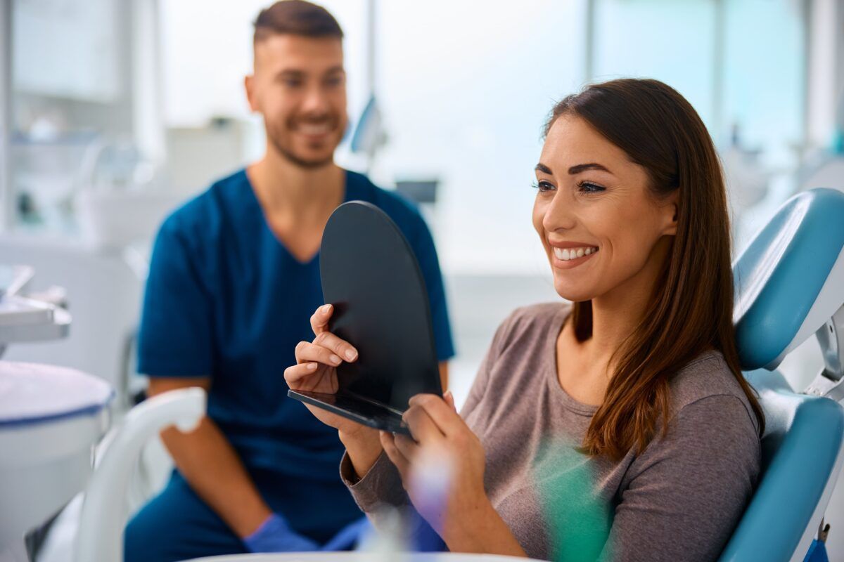 Satisfied woman looking herself in a mirror during a visit to the dentist