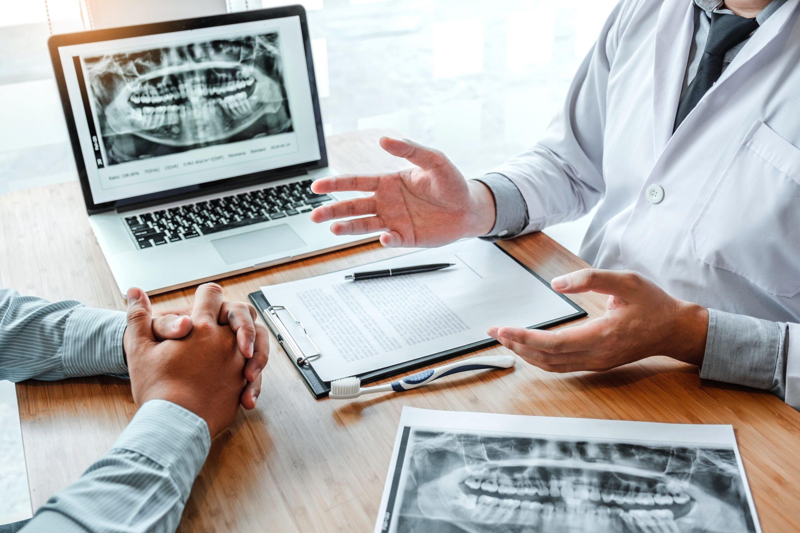 Dentist with male patient presenting discussing dental problems x-ray image