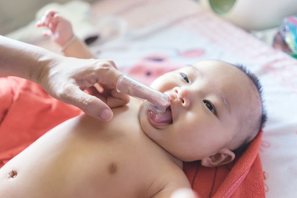 Mother use finger to clean baby tongue and gum with the clean gauze