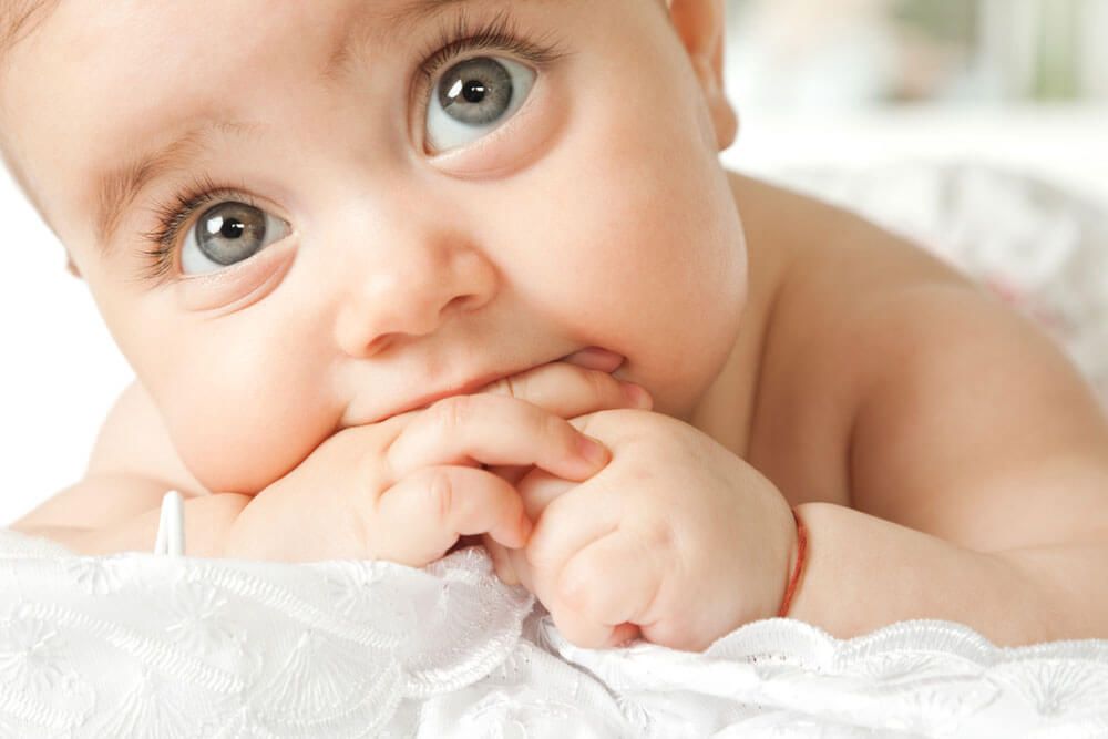 adorable little baby face lying with hand in mouth