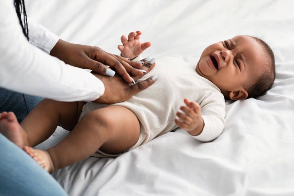 mother doing belly massage for crying baby