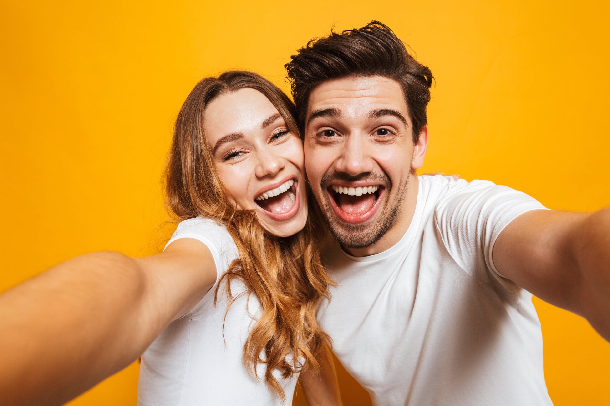 joyful man and woman laughing and taking selfie photo