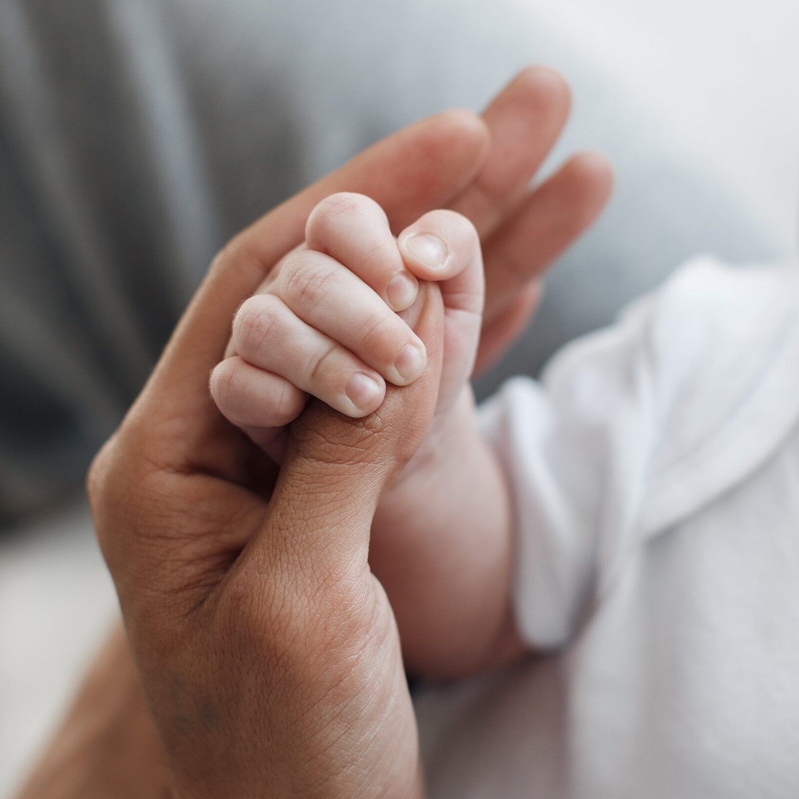 little infant's hand holding parent's hand