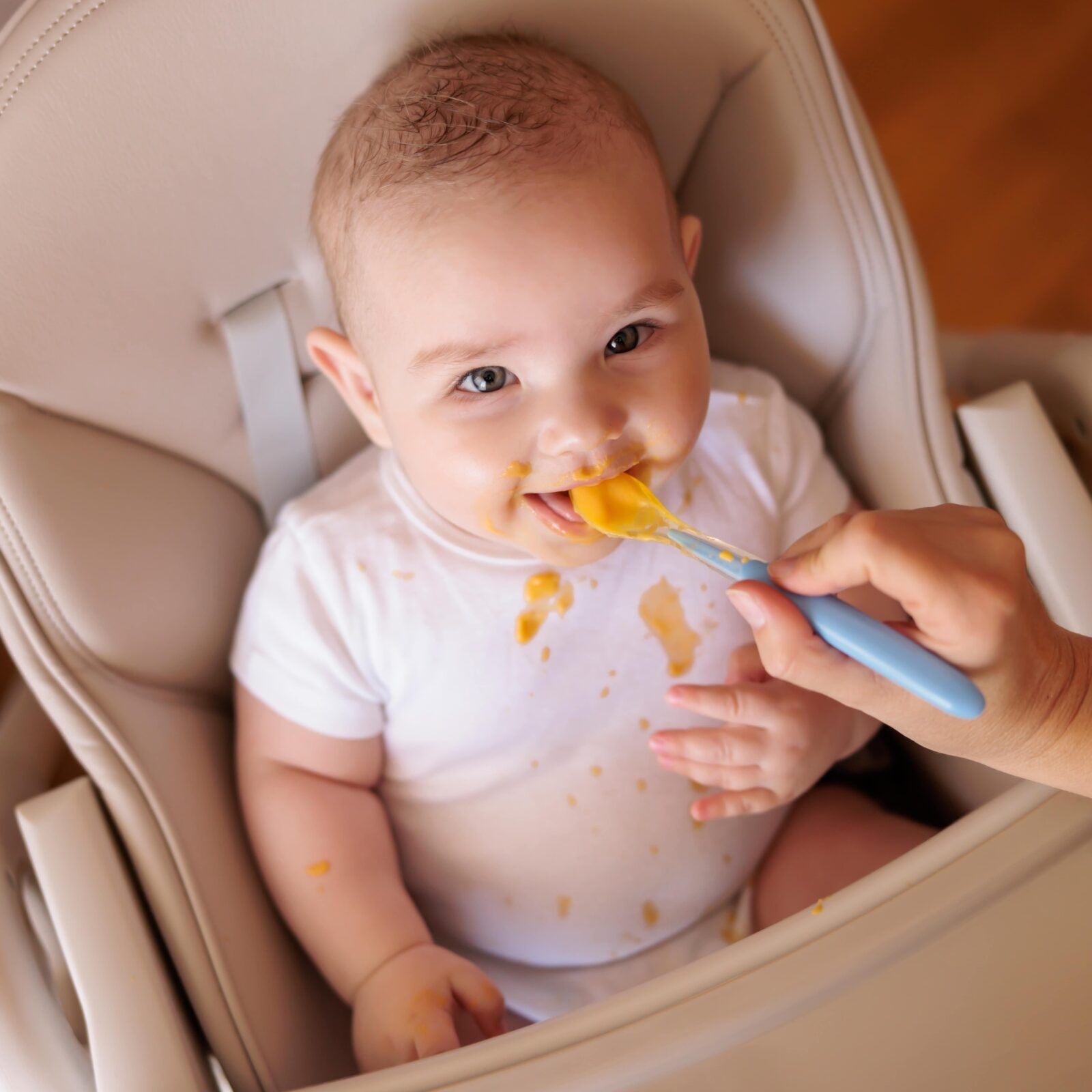 mother feeding cheerful baby boy