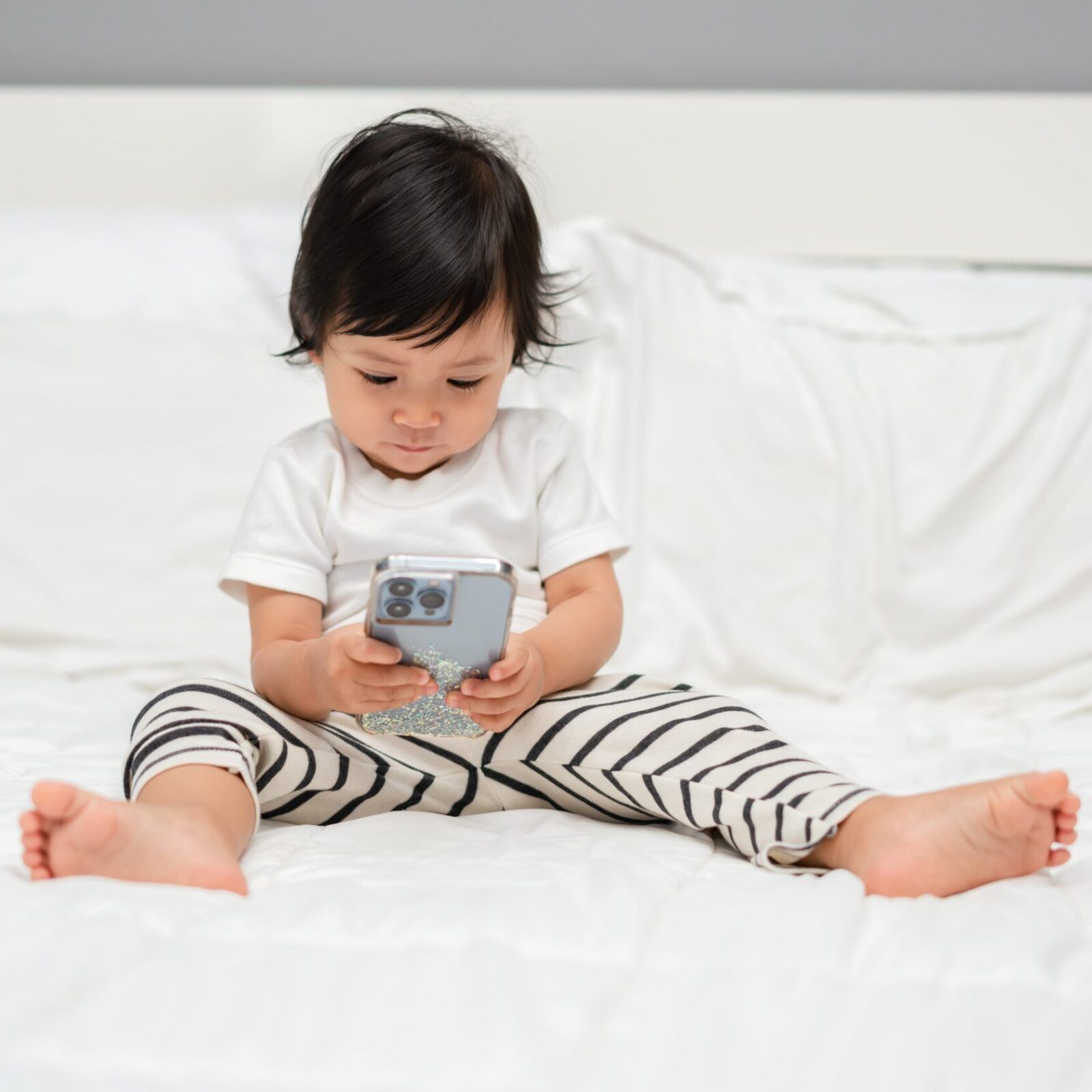 toddler baby watching smartphone on a bed