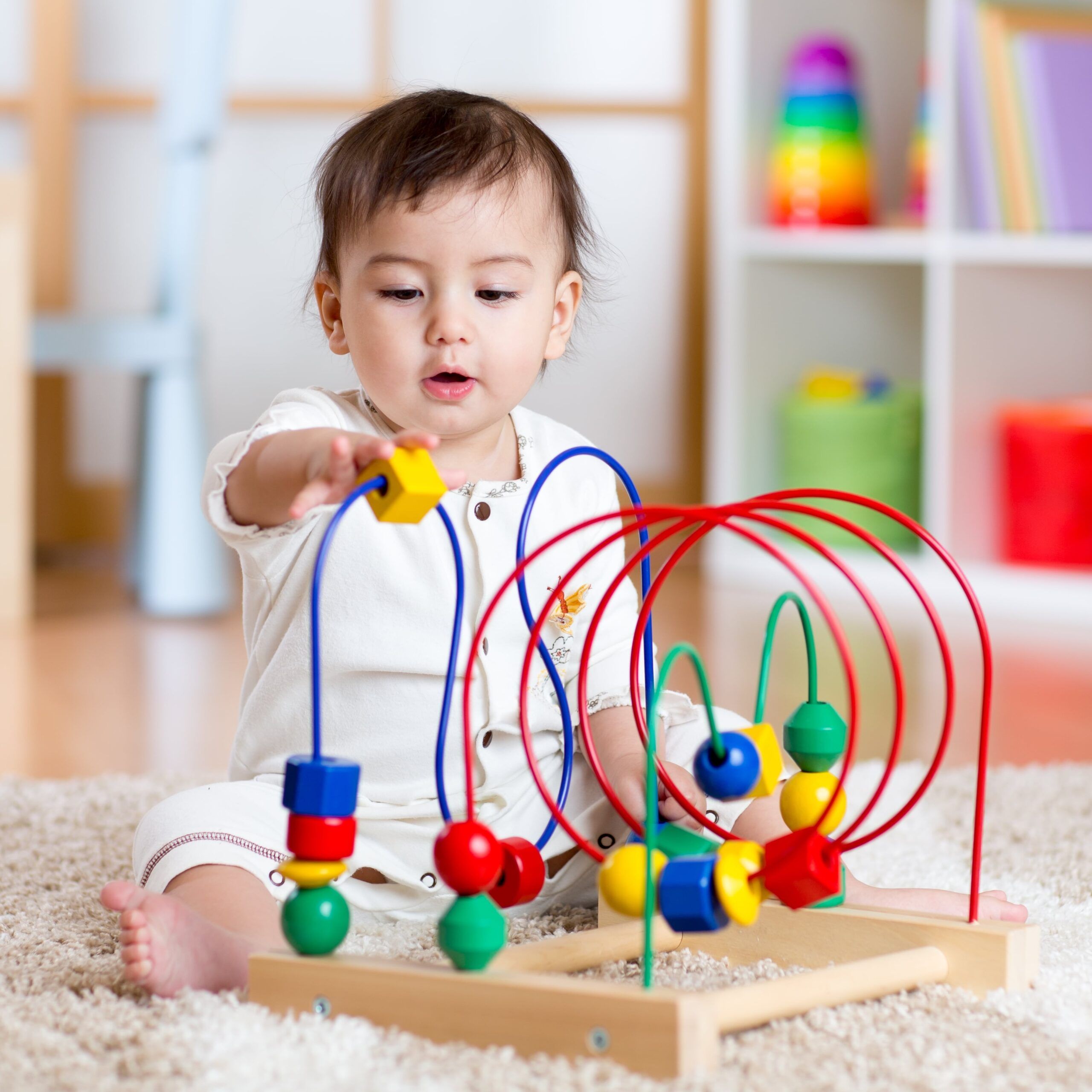 baby girl playing with educational toy in nursery