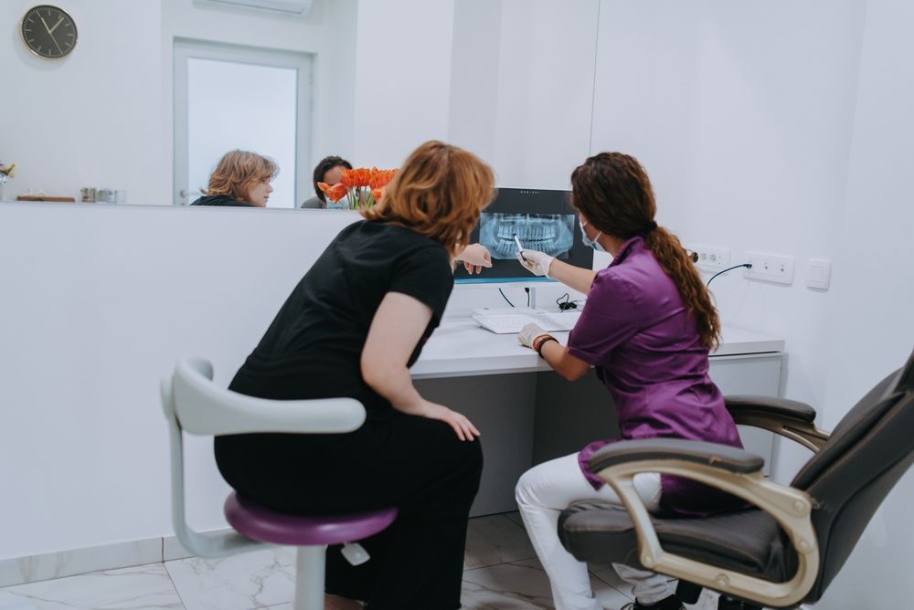 a dentist and a young patient engage in a collaborative consultation, exploring new tooth shades and discussing treatment options using a computer