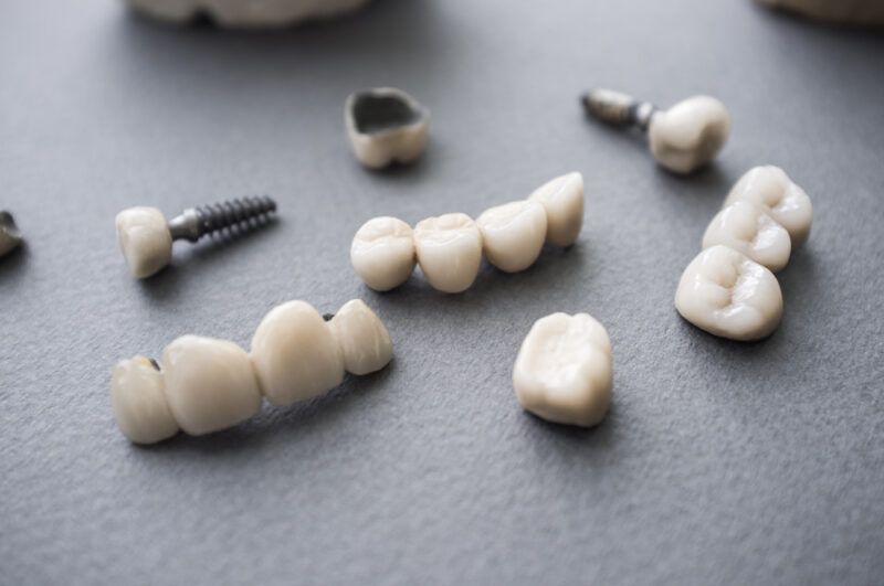 Ceramic dentures and crowns on gray background.