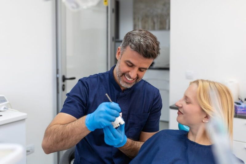 Dentist showing dental plaster mold to the patient. Dentist doctor showing jaw model at dental clinic