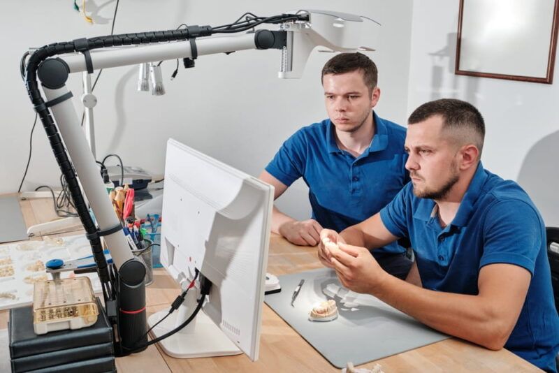 Dental technicians producing dental prosthesis under the microscope. The concept of prosthetics and implantology.
