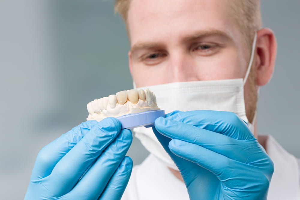 dental technician checks quality of denture parts in dental laboratory