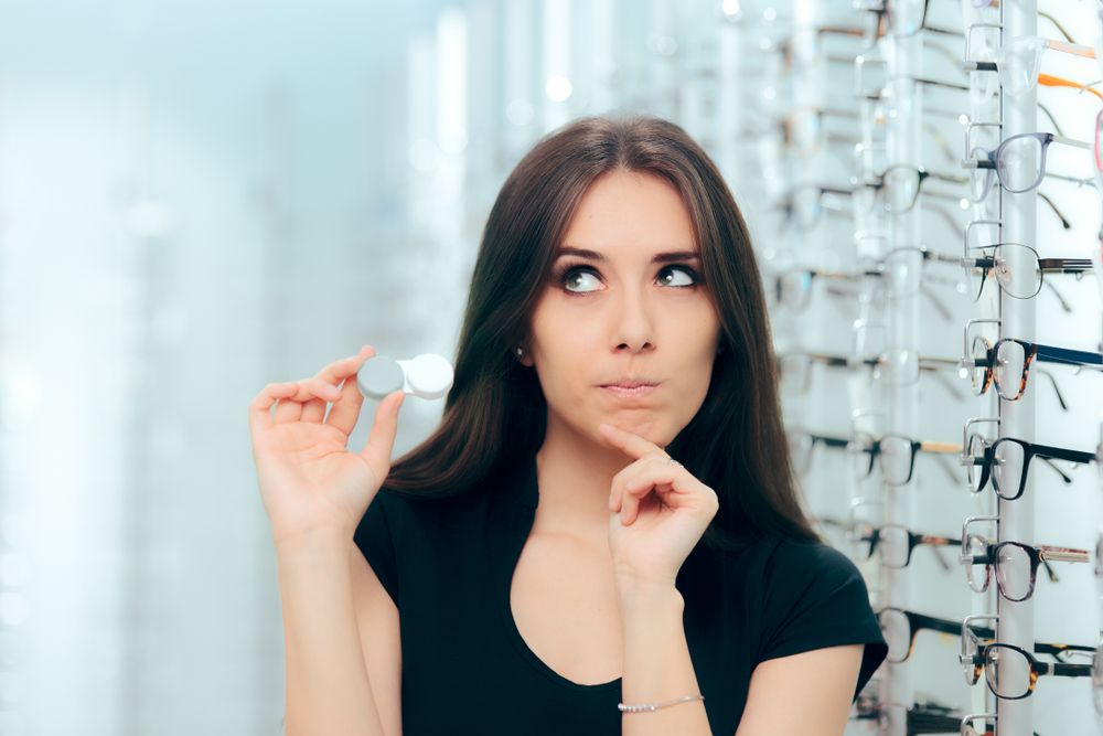 Woman Thinking to Choose Contact Lenses Over Eyeglasses. Girl considering the advantages and disadvantages of wearing contacts