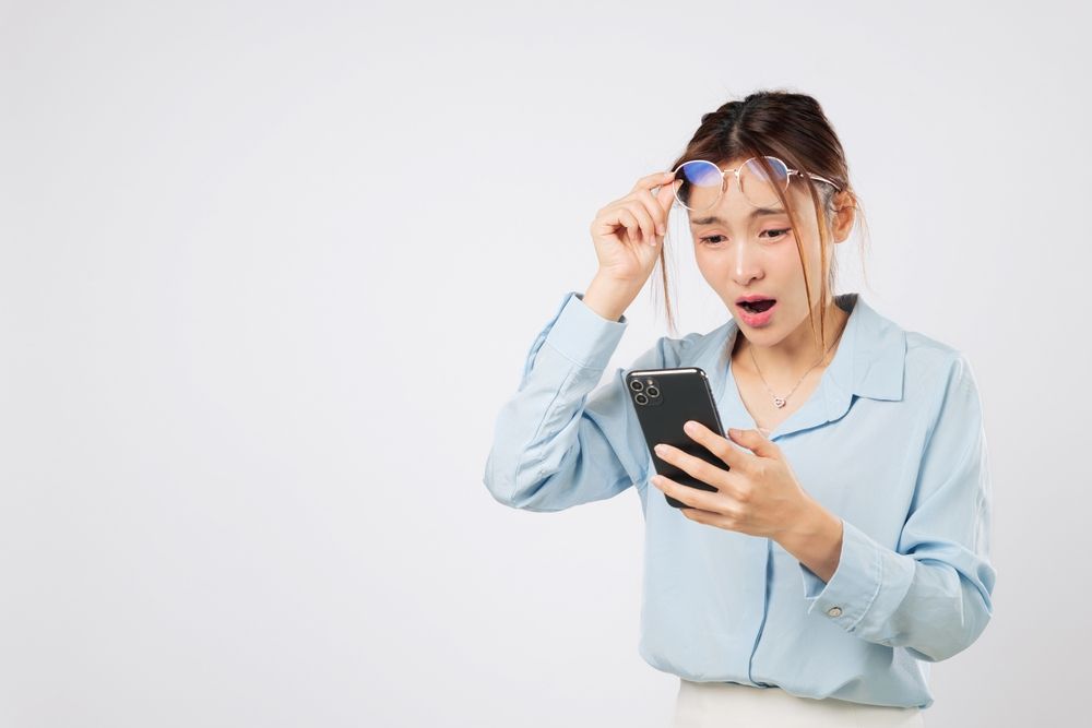 Vision problem woman holding glasses and looking at phone screen, blurred vision loss