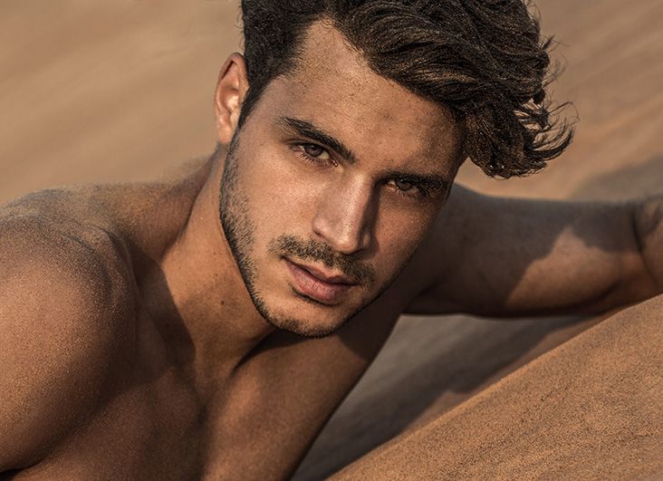 handsome topless male lying on the desert sand