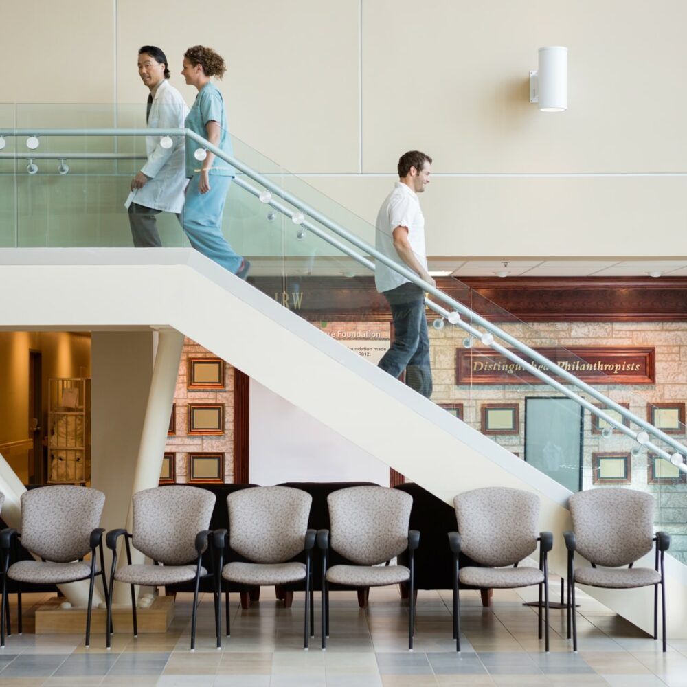 medical team and man using staircase in hospital