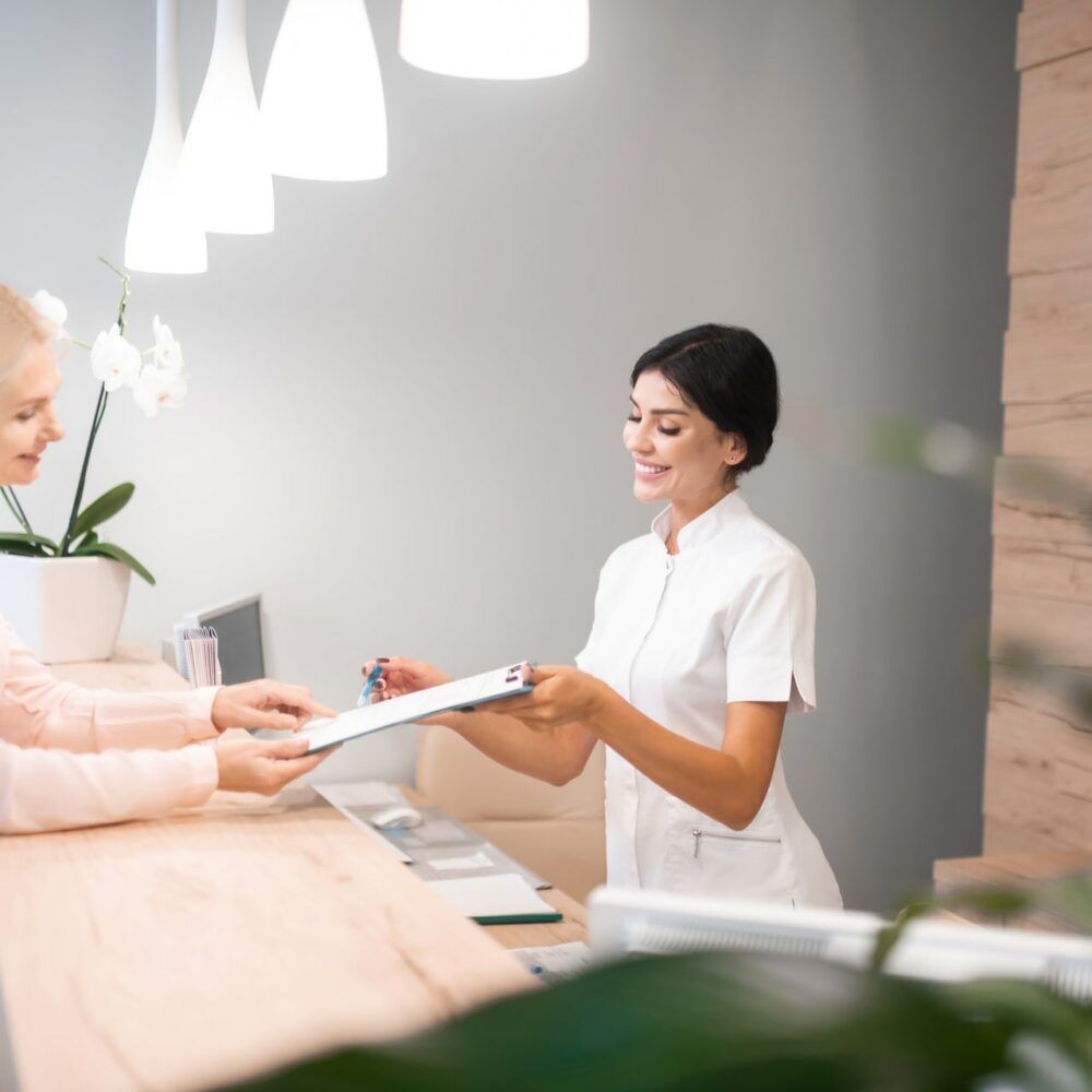 Cheerful receptionist showing the client way of filling up the form