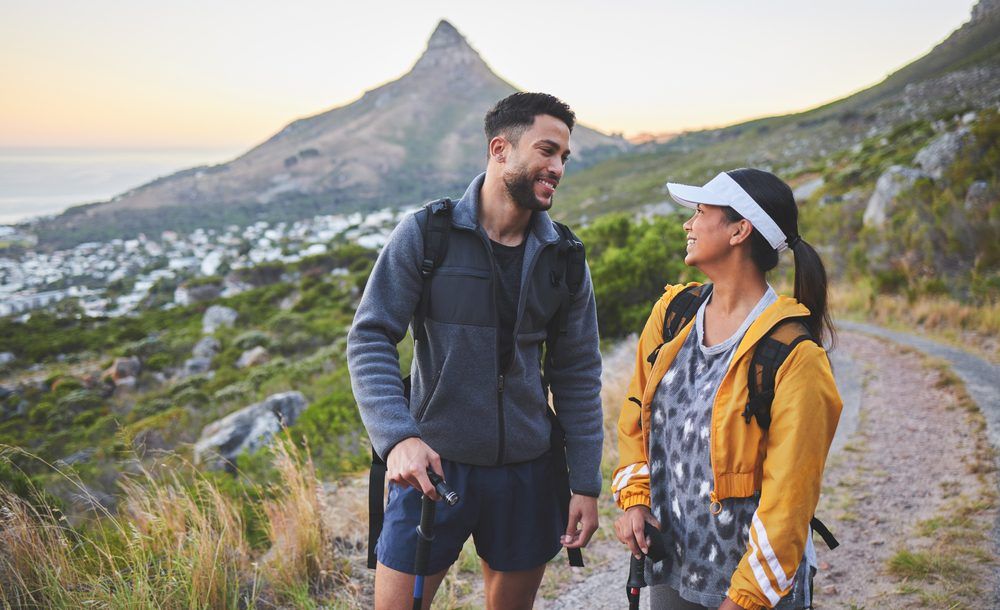 young couple hiking at sunset on a mountain