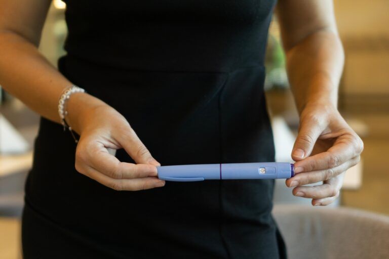 A woman in a black dress holding an ozempic pen, concept of medical treatment, modern healthcare, and weight loss solutions.