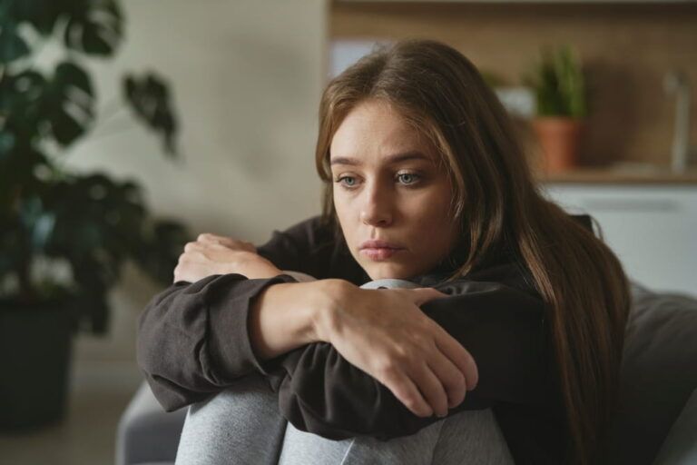 Caucasian sad woman sitting at the sofa with depression