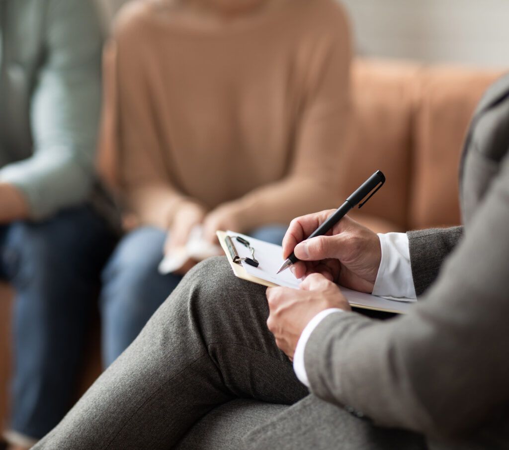 Consultant writing notes while spouses having session