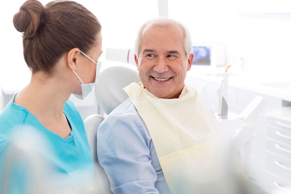 Older man discussing insurance with dental professional