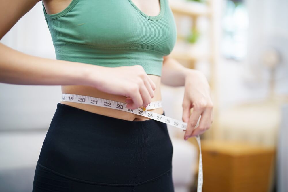 Slim woman measuring waist with measure tape