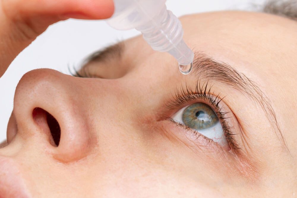 woman dripping her eye with medicinal drops