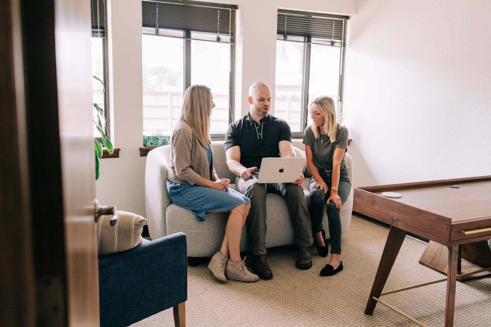three Zephyr Behavioral Health & Wellness therapists talking while looking at a laptop while sitting on a couch in the office